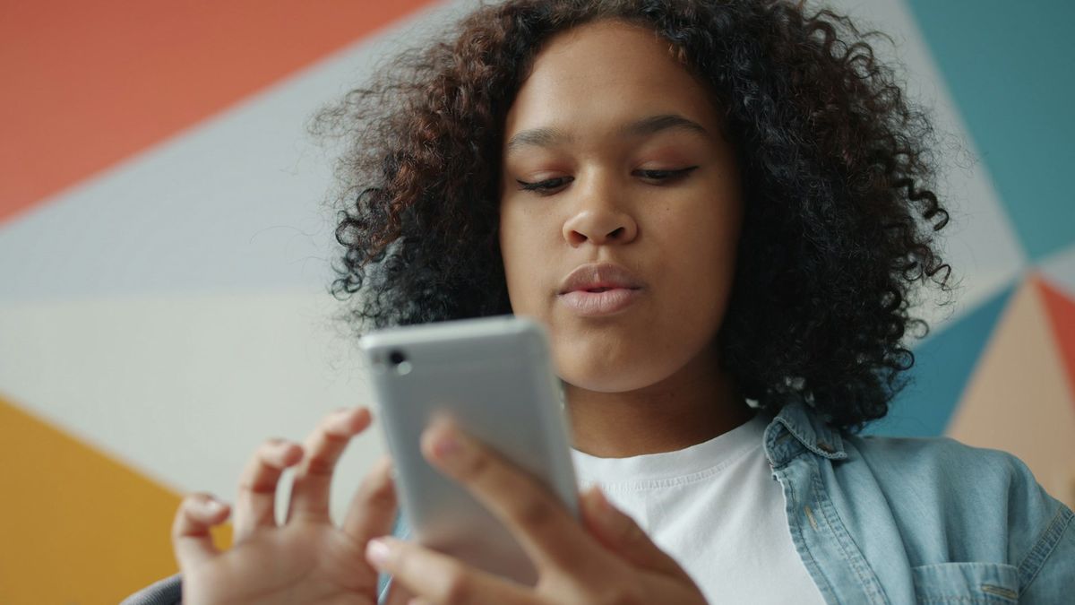 A teenager with curly hair taps through questions on her phone