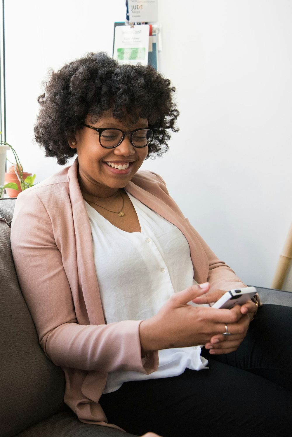 A woman at home smiles at her phone